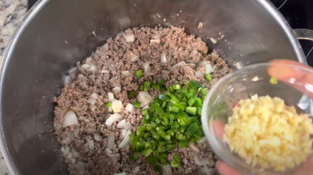 Adding onion , bell pepper and garlic to the beef